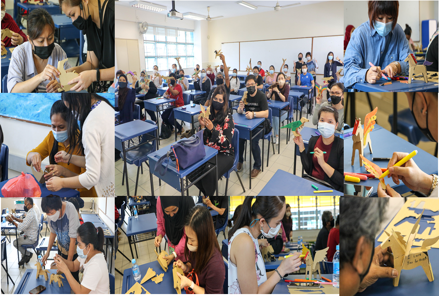 Students wearing masks sit in a classroom assembling and painting small wooden animal craft figures during a workshop.